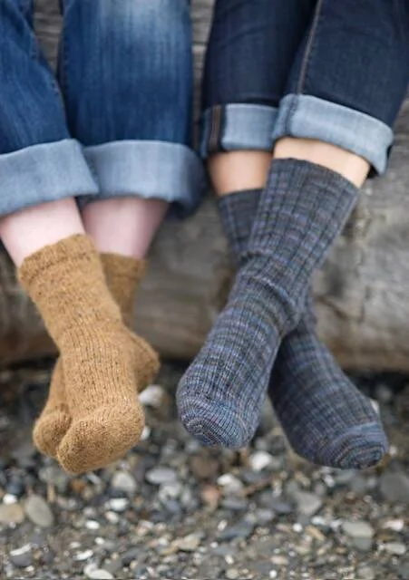 Two pairs of hand-knit socks, one tan and one blue